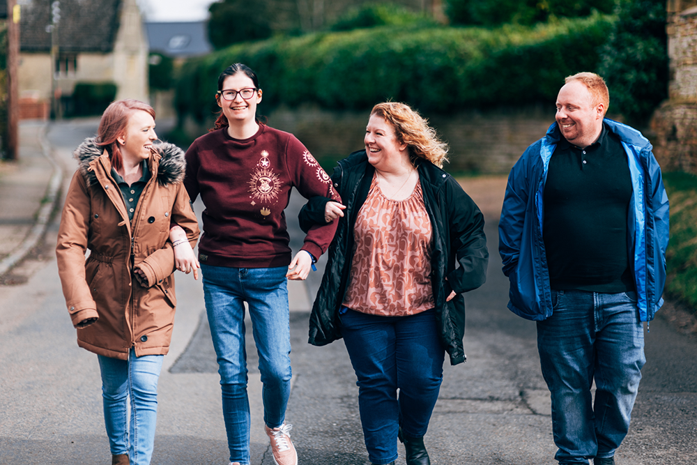 Residents linked arms with staff from Consensus Support, walking down a country road, laughing and enjoying their time together.