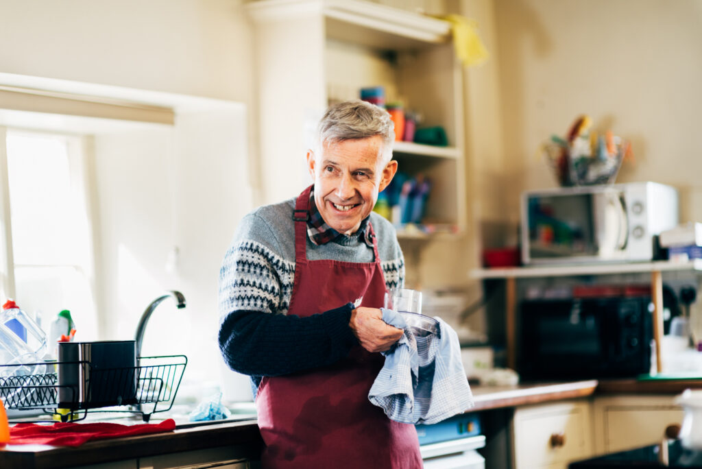 A Consensus Support resident smiling as they wash up, facing away from the camera, showcasing independence in daily activities.